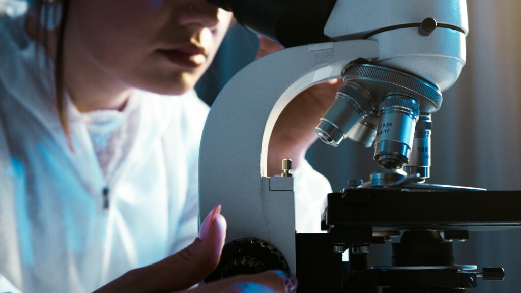 Scientist examining samples with a microscope in a laboratory setting.
